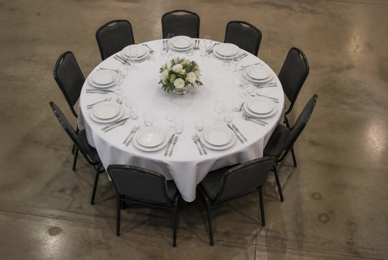 A large round banquet table set with ten covers and chairs tucked in, seen from above